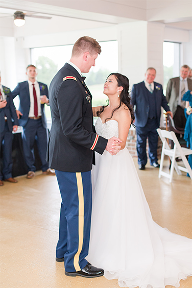 A bride and groom are dancing in front of other people.